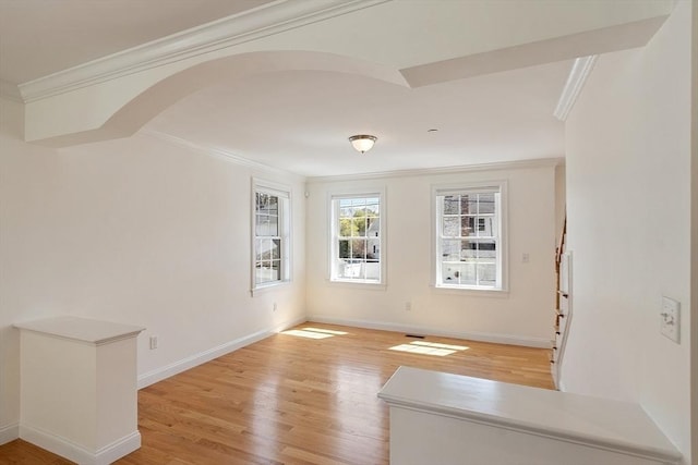 empty room with baseboards, ornamental molding, and light wood-style flooring