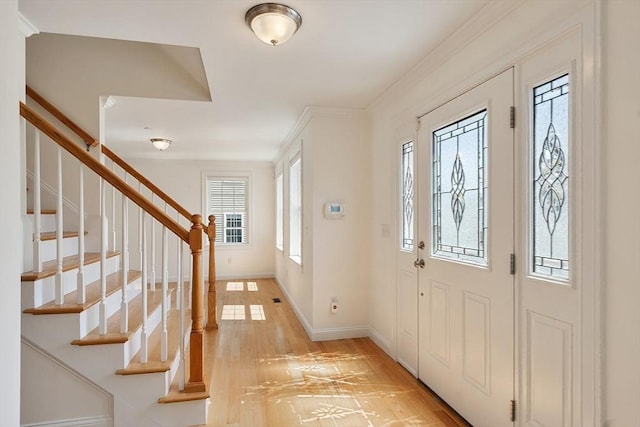entrance foyer featuring crown molding, light wood finished floors, stairs, and baseboards