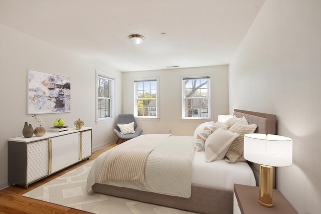 bedroom featuring visible vents, light wood-type flooring, and baseboards