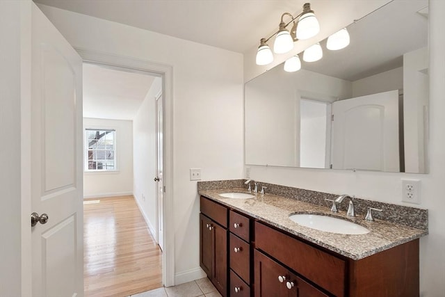 full bath featuring double vanity, baseboards, tile patterned flooring, and a sink