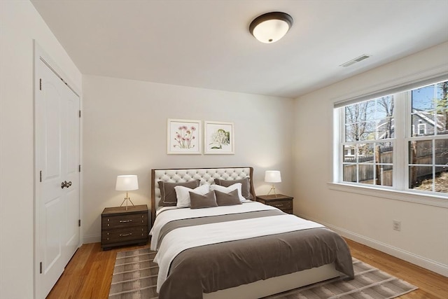 bedroom with wood finished floors, visible vents, and baseboards