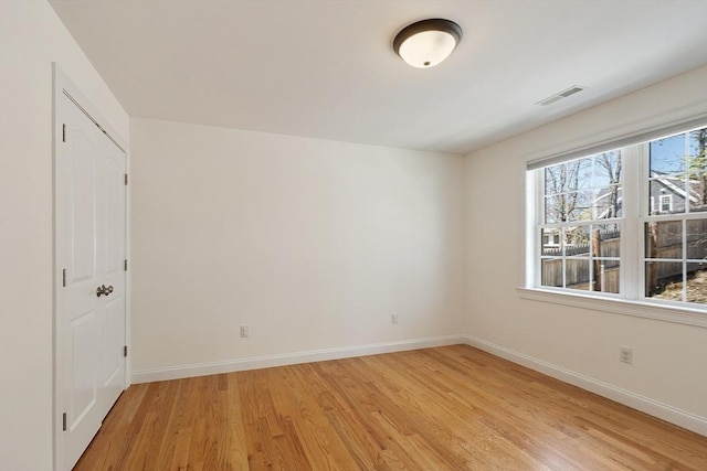 unfurnished room featuring baseboards, visible vents, and light wood-style flooring