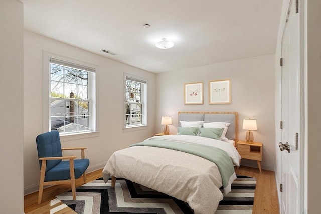 bedroom with baseboards, visible vents, and light wood finished floors