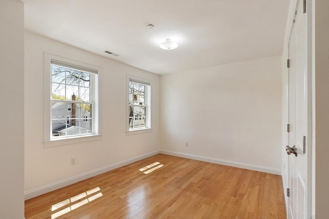 spare room with baseboards, visible vents, and light wood finished floors