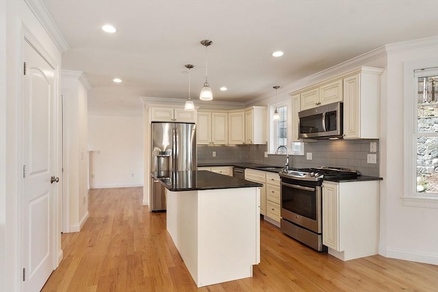 kitchen with stainless steel appliances, dark countertops, backsplash, a sink, and cream cabinetry