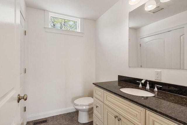bathroom featuring tile patterned flooring, toilet, vanity, baseboards, and visible vents