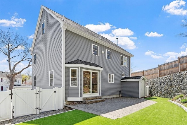 rear view of property featuring a gate, a storage unit, a patio, and a fenced backyard