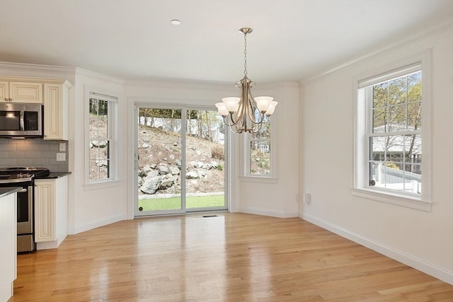 unfurnished dining area with a wealth of natural light, light wood-style floors, a notable chandelier, and baseboards