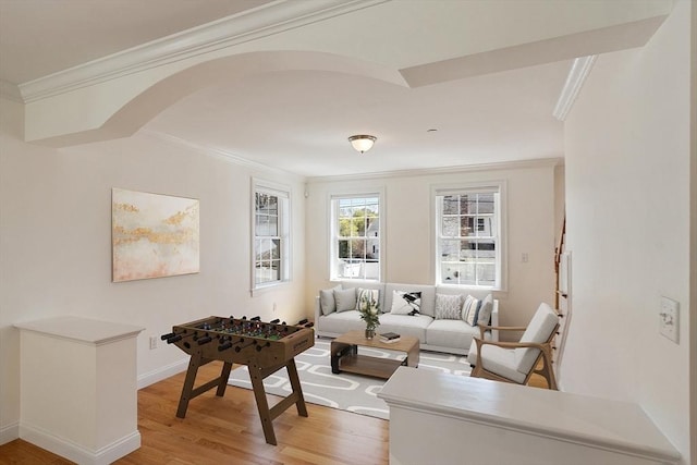 living room with ornamental molding, baseboards, and light wood-style floors