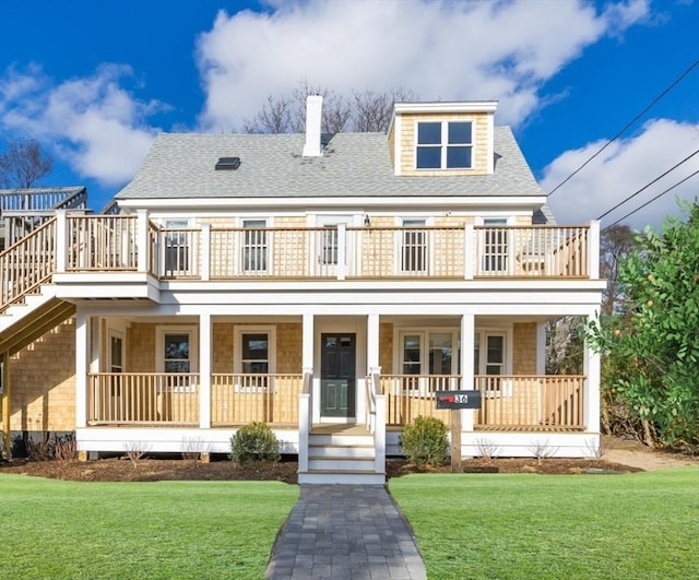 view of front of house featuring a balcony, a front yard, and covered porch