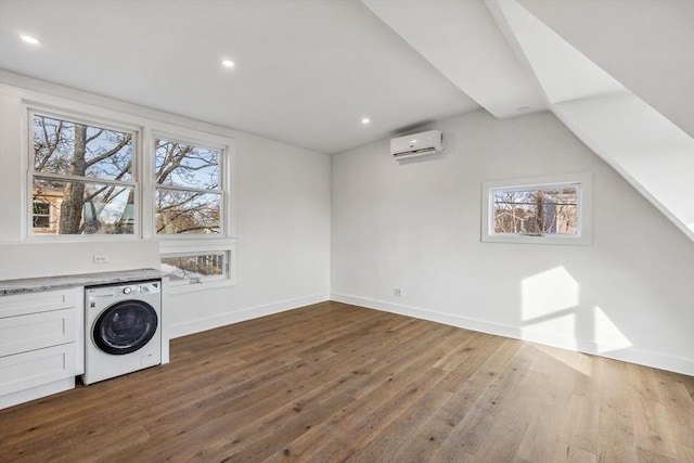 laundry area with hardwood / wood-style flooring, washer / clothes dryer, and a wall unit AC