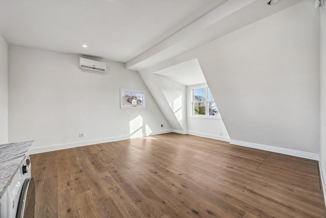 bonus room featuring lofted ceiling, a wall mounted air conditioner, dark hardwood / wood-style flooring, and washer / dryer