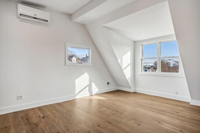 bonus room with a healthy amount of sunlight, a wall mounted air conditioner, and light wood-type flooring