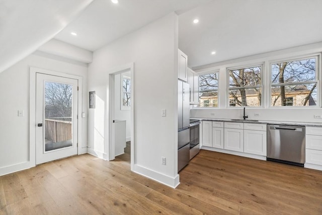 kitchen with light wood-type flooring, white cabinets, and appliances with stainless steel finishes