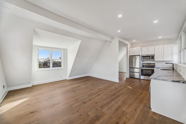 kitchen with sink, light stone counters, dark hardwood / wood-style flooring, stainless steel appliances, and white cabinets