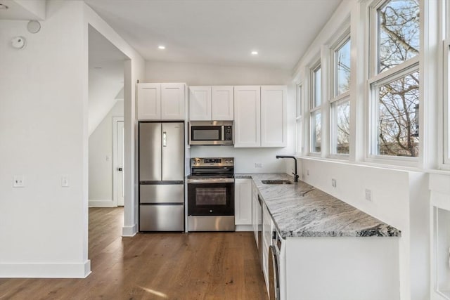 kitchen featuring sink, appliances with stainless steel finishes, white cabinetry, light stone countertops, and dark hardwood / wood-style flooring