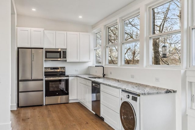 kitchen with stainless steel appliances, white cabinetry, sink, and washer / clothes dryer