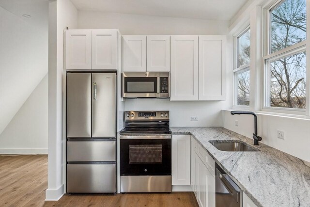 kitchen featuring white cabinetry, sink, stainless steel appliances, and light stone countertops