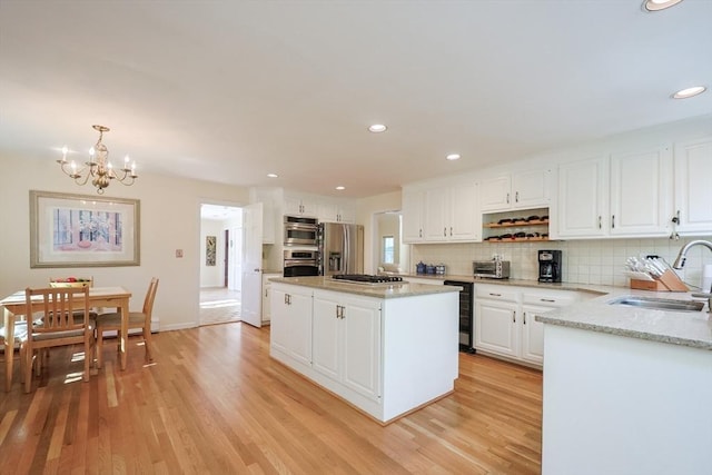 8 Fieldstone Ln, Natick, MA 01760 - kitchen featuring open shelves, light wood-type flooring, a sink, appliances with stainless steel finishes, and a notable chandelier