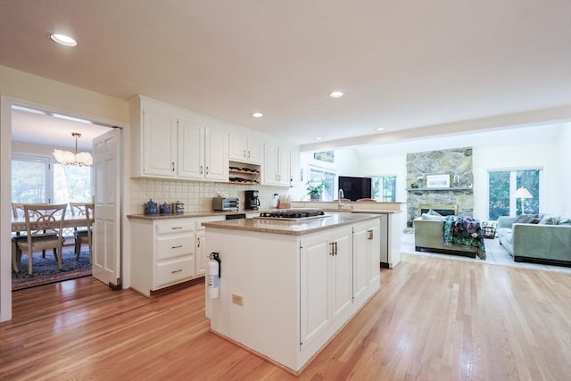 8 Fieldstone Ln, Natick, MA 01760 - kitchen with stainless steel gas cooktop, a center island, white cabinets, light wood-style flooring, and a notable chandelier