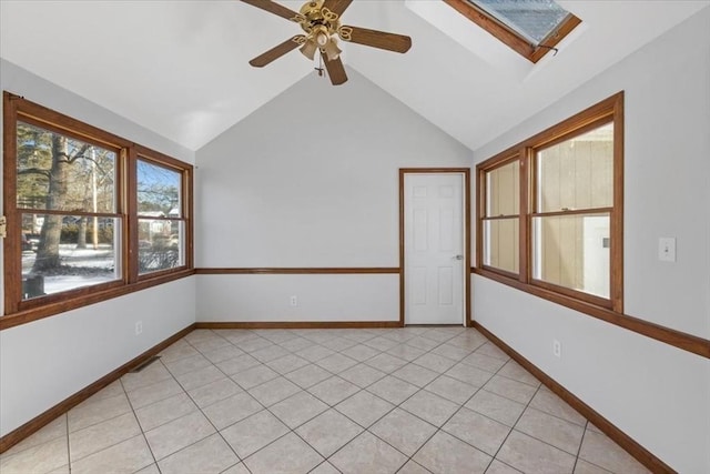 spare room with light tile patterned flooring, ceiling fan, and lofted ceiling with skylight