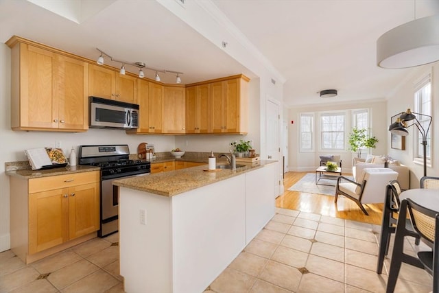 kitchen with sink, crown molding, light stone countertops, stainless steel appliances, and light tile patterned floors