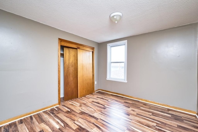 101 Cory St, Fall River, MA 02720 - unfurnished bedroom featuring wood finished floors, baseboards, a closet, and a textured ceiling