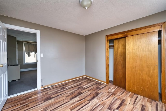 101 Cory St, Fall River, MA 02720 - unfurnished bedroom with wood finished floors, a closet, baseboards, and a textured ceiling
