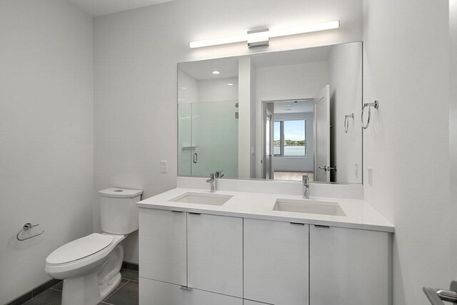 full bathroom with toilet, double vanity, a sink, and a stall shower