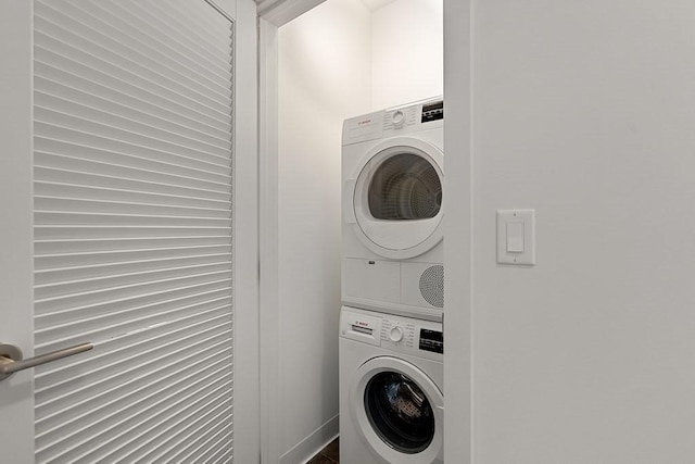 laundry area with stacked washer and clothes dryer, laundry area, and baseboards