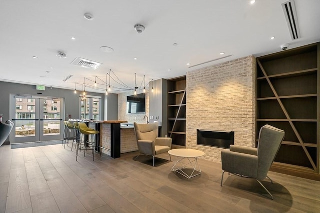 interior space featuring french doors, visible vents, built in shelves, and hardwood / wood-style flooring