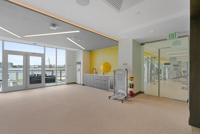 game room featuring light carpet, a water view, a wall of windows, and french doors