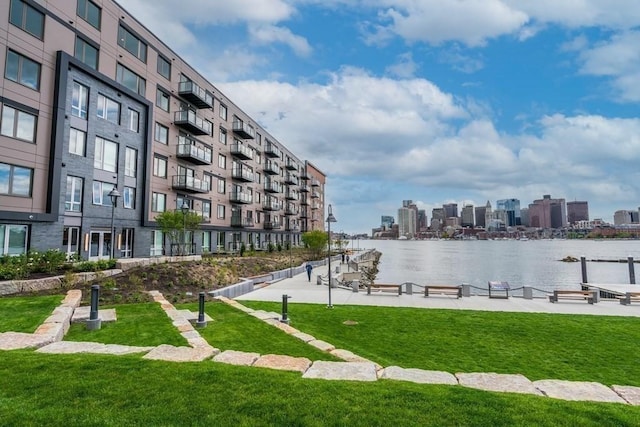 view of community with a water view, a yard, and a city view