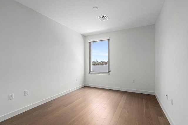 unfurnished room featuring visible vents, baseboards, and dark wood-type flooring