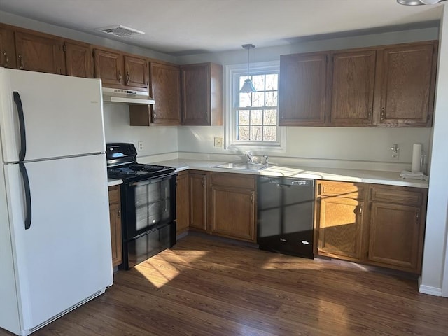 kitchen featuring visible vents, dark wood finished floors, under cabinet range hood, black appliances, and a sink