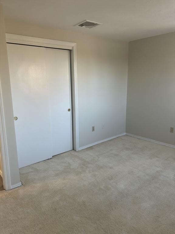 unfurnished bedroom with light carpet, visible vents, and a closet