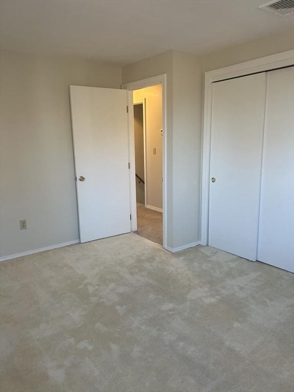 unfurnished bedroom with carpet, a closet, visible vents, and baseboards