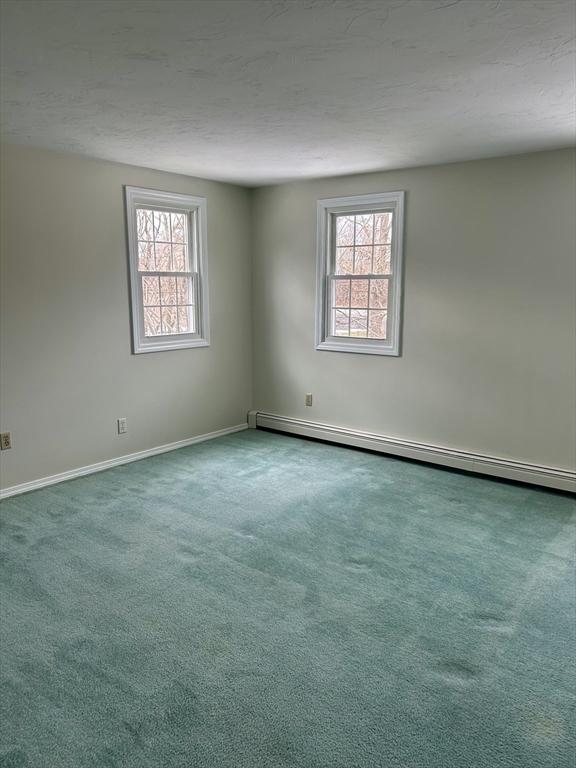 unfurnished room with carpet, baseboards, plenty of natural light, and baseboard heating