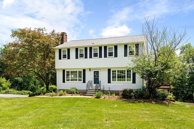 colonial home with a chimney and a front yard