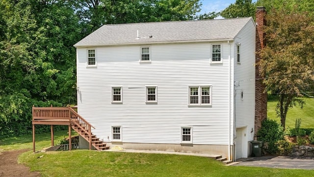 back of property featuring a chimney, a lawn, stairway, a garage, and a wooden deck