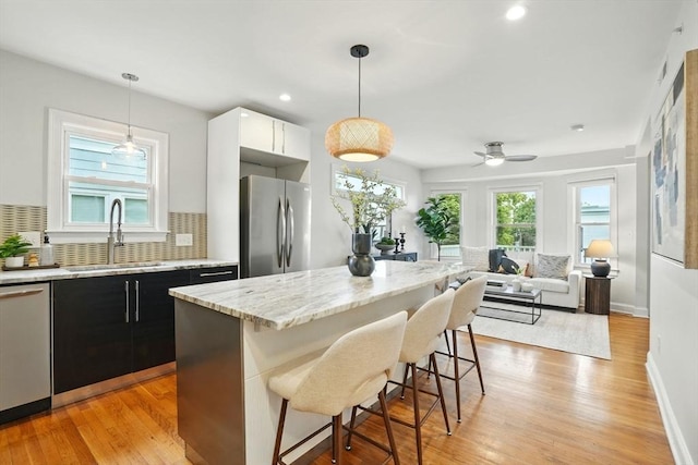 33 Century St Unit 3, Somerville, MA 02145 - kitchen featuring appliances with stainless steel finishes, a kitchen breakfast bar, light stone counters, tasteful backsplash, and light wood finished floors