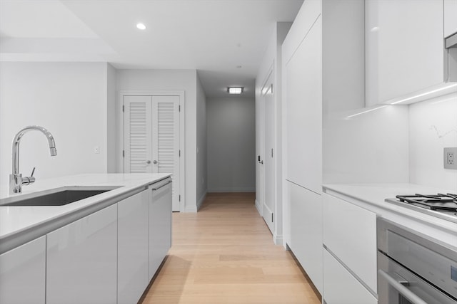 kitchen with white cabinetry, light hardwood / wood-style floors, appliances with stainless steel finishes, and sink