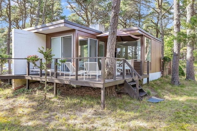 rear view of house featuring a lawn and a deck