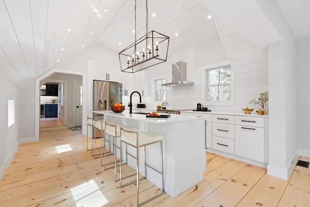 540 S Orleans, Orleans, MA 02653 - kitchen with wall chimney range hood, a sink, stainless steel refrigerator with ice dispenser, light wood finished floors, and a kitchen bar
