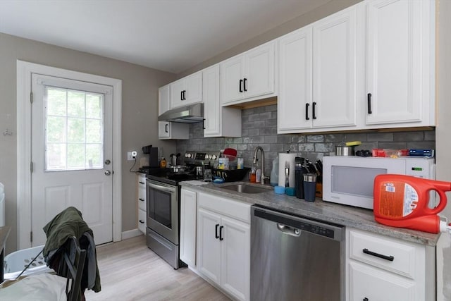 1 Commonwealth Ave, Sturbridge, MA 01518 - kitchen with stainless steel appliances, under cabinet range hood, decorative backsplash, white cabinetry, and light wood finished floors