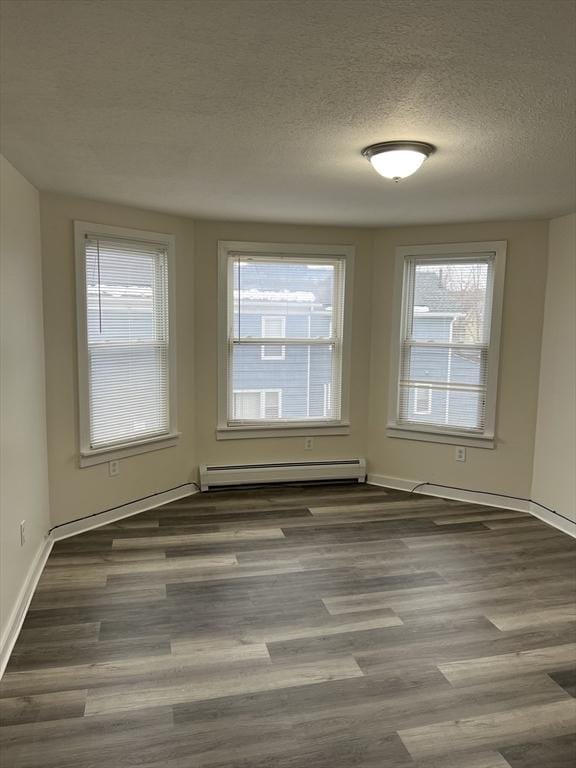 empty room with a baseboard heating unit, a textured ceiling, and wood finished floors