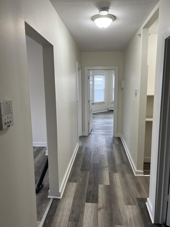 hall featuring dark wood-style floors, baseboards, and a textured ceiling