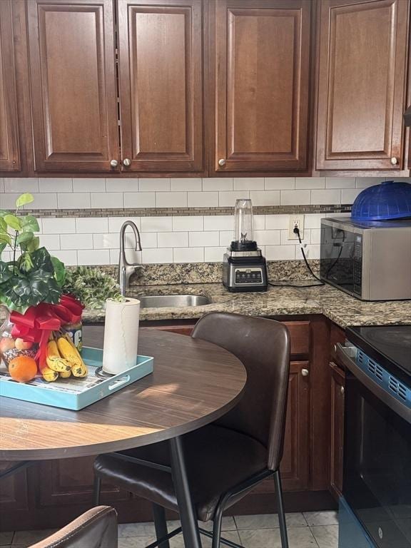 kitchen with sink, stainless steel appliances, dark stone countertops, and tasteful backsplash