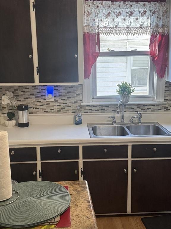 kitchen featuring sink, backsplash, and wood-type flooring