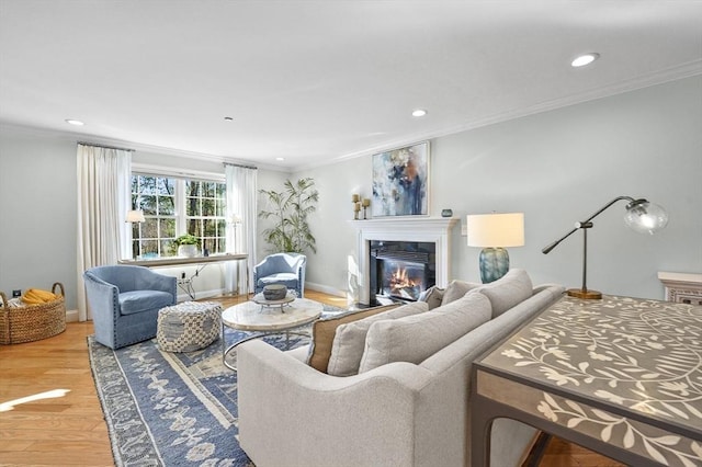 living area featuring baseboards, ornamental molding, wood finished floors, recessed lighting, and a glass covered fireplace